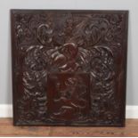 A carved mahogany panel detailing a heraldic crest featuring lion rampant and helmet surrounded by