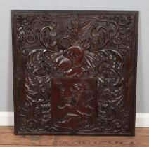 A carved mahogany panel detailing a heraldic crest featuring lion rampant and helmet surrounded by