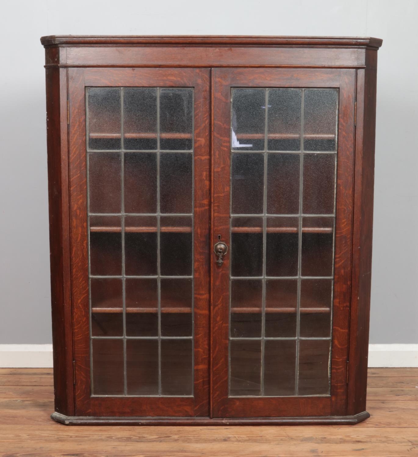 A large Georgian style oak wall mounted corner cupboard, with twin lead glazed doors. Height: 127cm,