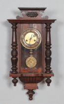 A mahogany cased wall clock with turned supports and carved detail.