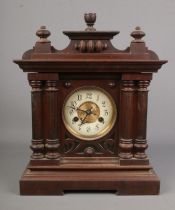 An oak cased mantel clock with brass and enamel dial flanked by twin pillars. Includes key and