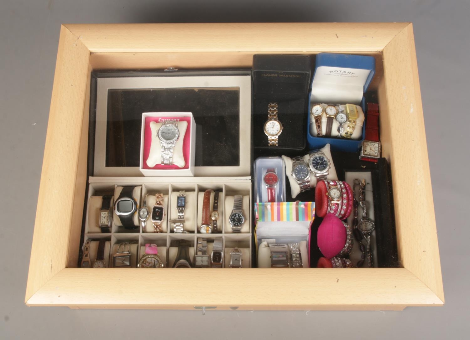 A table top display case containing an assortment of watches, mainly quartz examples. To include