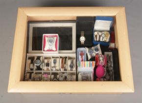 A table top display case containing an assortment of watches, mainly quartz examples. To include