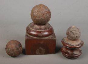 Three small canon balls with two mounted on wooden bases.