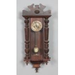 A mahogany wall clock with enamel face, turned columns and carved detail. Hx86cm approx