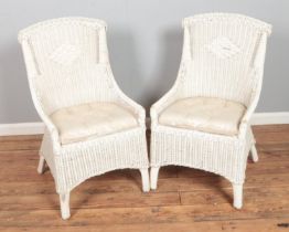 A pair of cream wicker patio chair with cushioned seats.