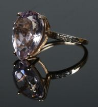 A 9ct gold dress ring set with a large pink coloured stone, possibly Morganite. Having three small