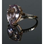 A 9ct gold dress ring set with a large pink coloured stone, possibly Morganite. Having three small