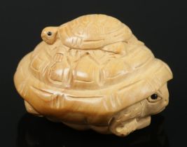 A hand carved hardwood netsuke of a baby turtle sitting on an adult turtle.