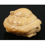 A hand carved hardwood netsuke of a baby turtle sitting on an adult turtle.