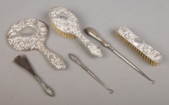 A three piece silver filled dressing table set; having scrolled and masked decoration, together with