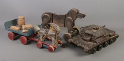 A collection of wooden hand made toys. Includes horse and cart, tank and pull along dog. Similar