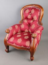 An upholstered button back child's/dolls chair featuring carved floral motif.