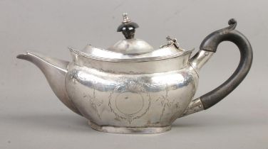 An Edwardian silver teapot of squat form, featuring ebonised handle, swag and bow engraving and