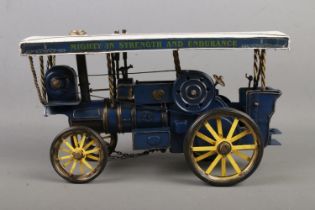 A model steam engine painted in white and blue with motto 'Mighty in Strength and Endurance,