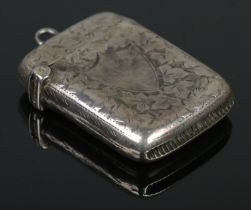 A late Victorian silver vesta case, engraved with ivy leaf decoration and blank shield crest to