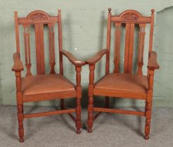 A pair of oak carved open armchairs with drop in leather seats.