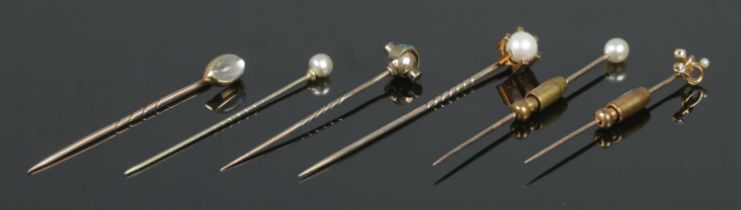 Six gold stick pins, including examples set with diamonds, turquoise stones and pearls. Total