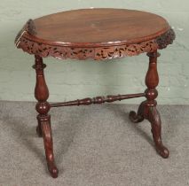 An oval oak occasional table with heavily carved frieze on twin pedestal supports and central