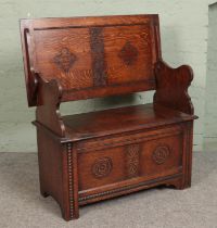 A carved oak monks bench, with detailing to back rest and front. Featuring folding top and under