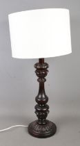 A decorative carved table lamp with cream fabric shade.