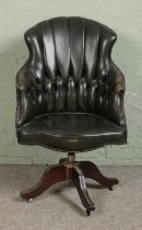 A late 20th century green leather button back swivel desk chair on a swivel base and castors.