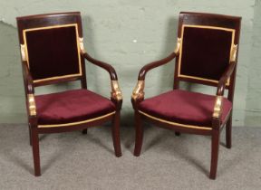 A pair of Empire style chairs with carved dolphins to arms with gilt details on curved square