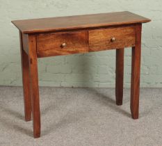 A mahogany two drawer console table featuring tapered supports. Approx. dimensions 94cm x 37.5cm x