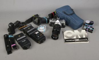 An Olympus OM-2 MD SLR camera fitted with OM-System Zuiko lens along with variety of accessories