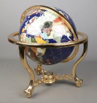 A large modern gemstone globe containing various minerals and semi-precious gems with compass