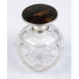 A globular cut glass scent bottle with silver and tortoise shell top.