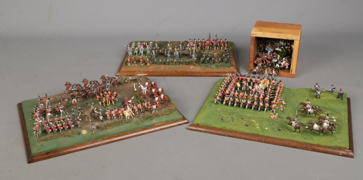 A large quantity of miniature soldiers mounted on three boards displayed as battle scenes. For