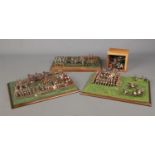 A large quantity of miniature soldiers mounted on three boards displayed as battle scenes. For