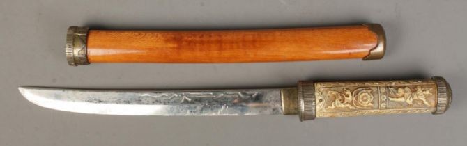 A reproduction Japanese Wakizashi short sword featuring carved decoration to handle and floral brass