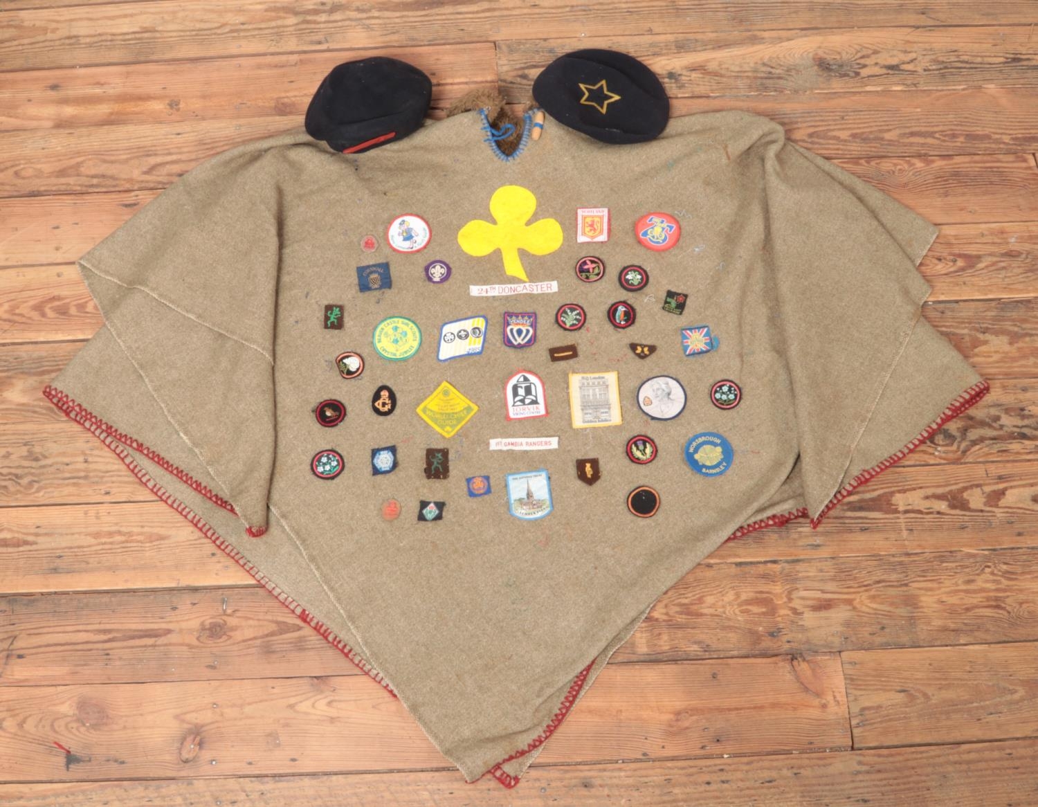 A vintage girl guides poncho, with a large collection of badges and two berets.