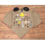 A vintage girl guides poncho, with a large collection of badges and two berets.