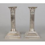 A pair of early Twentieth Century silver filled candlesticks, modelled as Corinthian columns.