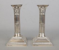 A pair of early Twentieth Century silver filled candlesticks, modelled as Corinthian columns.