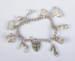 A silver charm bracelet with heart shaped clasp. Having silver and white metal charms. 41g.