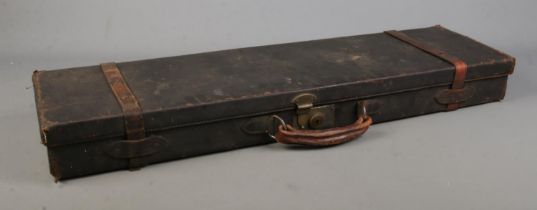An antique leather gun case, housing an assortment of accessories, including cleaning rods.