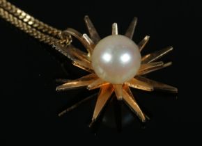 An 18ct Gold starburst shape pendant, set with central pearl, suspended on an 18ct Gold chain. Total