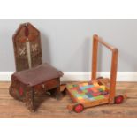 A small wooden child's chair decorated with swords and arrows with a vintage push trolley with