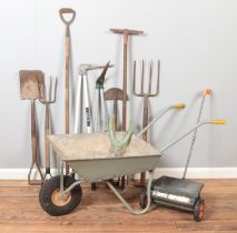 A collection of garden tools. Includes wheel barrow, lawn spreader, Wilkinson Sword etc.