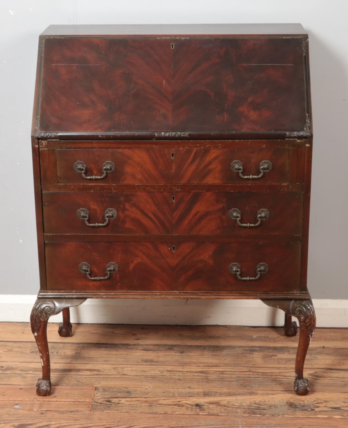 A mahogany three drawer bureau with fitted interior raised on ball and claw feet.