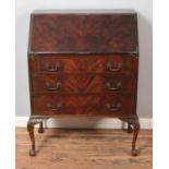 A mahogany three drawer bureau with fitted interior raised on ball and claw feet.