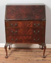 A mahogany three drawer bureau with fitted interior raised on ball and claw feet.