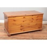 A pine blanket box raised on ball feet featuring decorative brass handles. Approx. dimensions