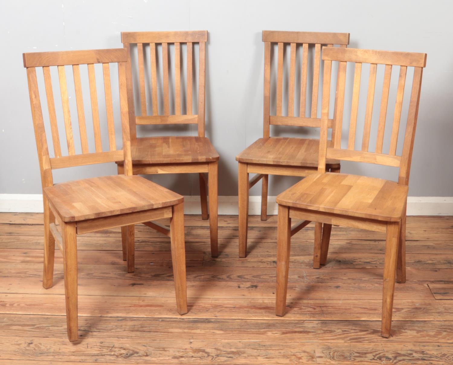 A set of four oak slat back dining chairs.