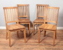 A set of four oak slat back dining chairs.