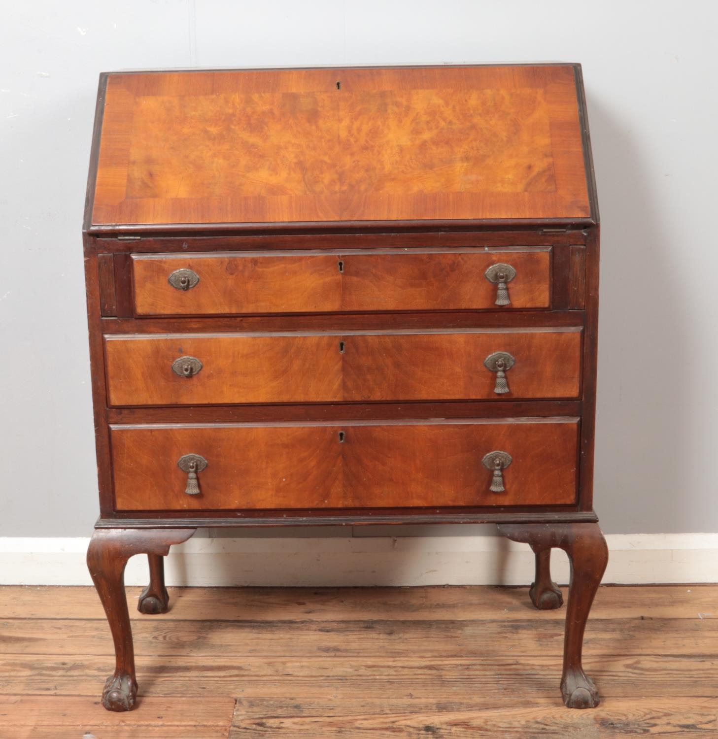 An early 20th century walnut bureau raised on ball and claw feet.